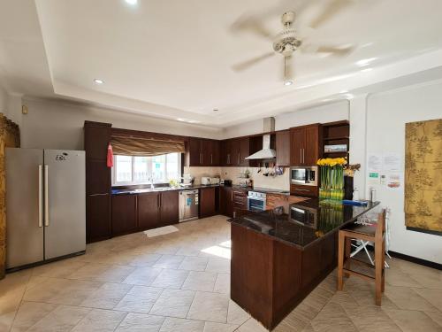 a kitchen with wooden cabinets and a stainless steel refrigerator at ปุณิกา พูล วิลล่า หัวหิน Punika Pool Villa Hua Hin in Hua Hin