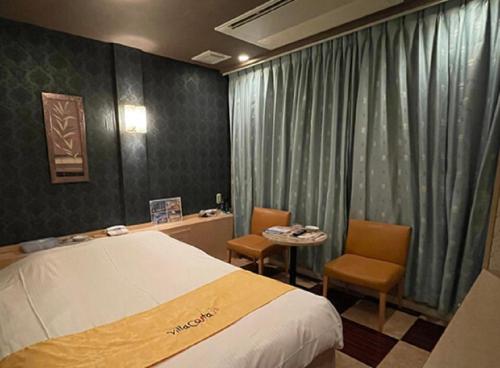 a hotel room with a bed and a table and chairs at ホテルヴィラコスタ Adult Only 男塾ホテルグループ in Hikone