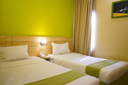 a hotel room with two beds and a green wall at Lorin Syariah Hotel Sentul in Bogor