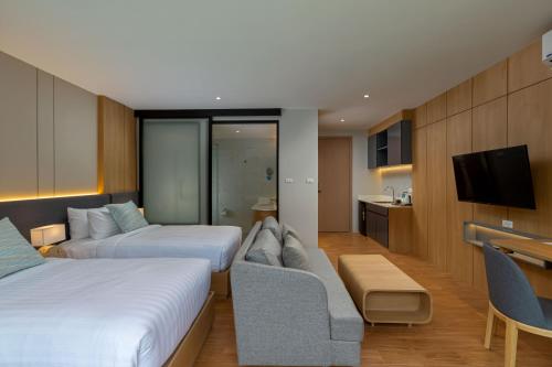 a hotel room with two beds and a couch at Wyndham Garden Naithon Phuket in Nai Thon Beach