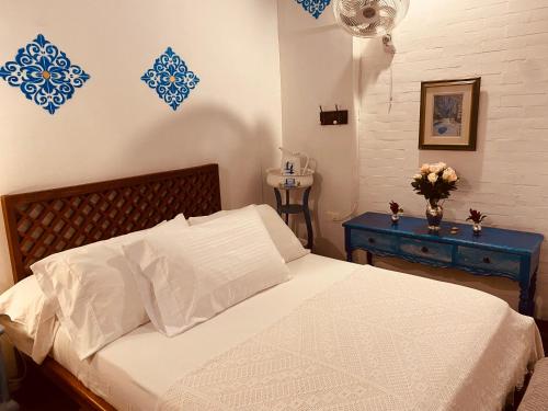 a bedroom with a white bed and a blue table at CASA SINNING-año1637 in Mompos