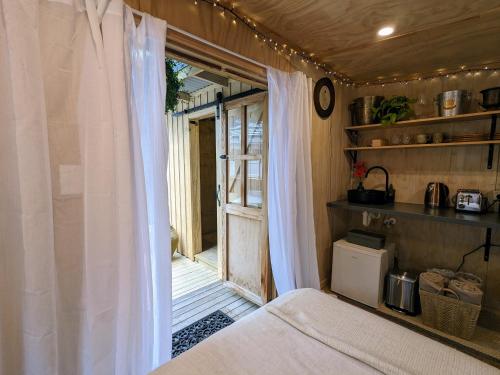 a bedroom with a bed and a window with curtains at Piccola Casa Fiorita in Mount Maunganui