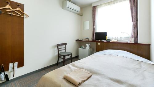 a bedroom with a bed and a chair and a window at Business Hotel Nishine in Hachimantai