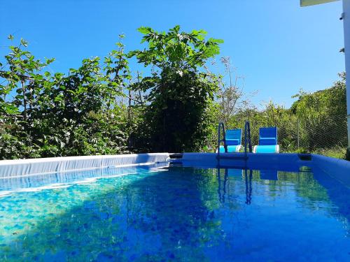 a swimming pool with two blue chairs in it at El-Sangha Studio 2mina pieds de la plage de baie du cap in Ruisseau Créole