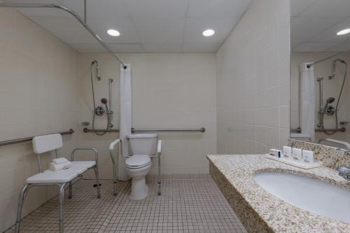 a bathroom with a toilet and a sink and a tub at Holiday Inn Des Moines-Airport Conf Center by IHG in Des Moines