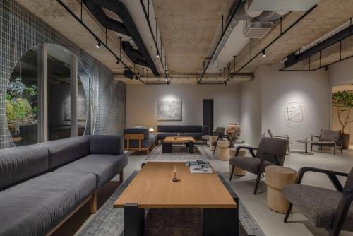 a living room with couches and tables and chairs at RAKURO Kyoto by THE SHARE HOTELS in Kyoto