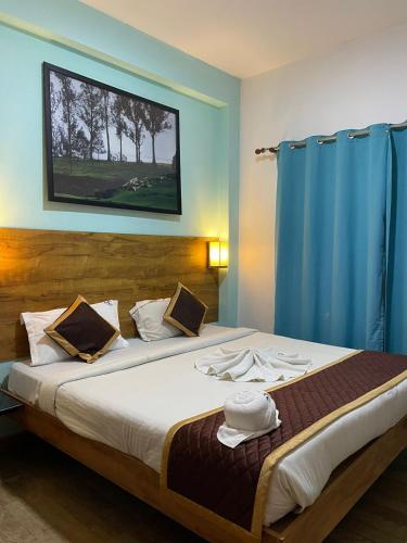 a bedroom with a large bed with a blue curtain at EDEN Paradisee in Ooty