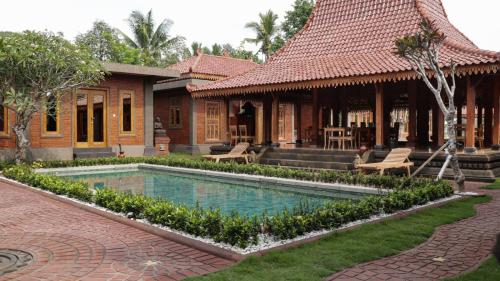 a resort with a swimming pool in front of a building at Rumah Dharma Boutique Villa in Magelang