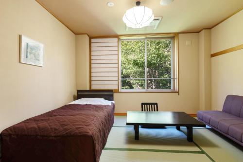 a bedroom with a bed and a couch and a window at KAMENOI HOTEL Tazawako in Senboku