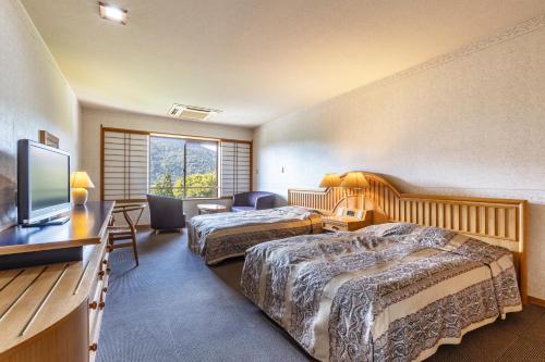 a hotel room with two beds and a flat screen tv at KAMENOI HOTEL Tazawako in Senboku