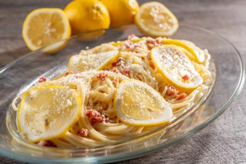 a glass plate of pasta with lemon slices on it at KAMENOI HOTEL Tazawako in Senboku