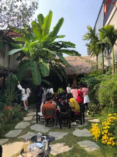 eine Gruppe von Menschen, die an Tischen im Garten sitzen in der Unterkunft Mai Chau Moonlight Ecohouse in Mai Châu