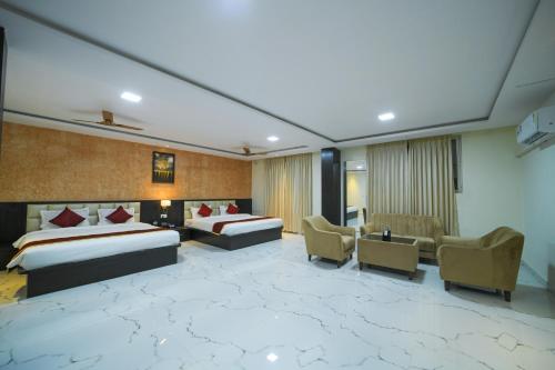 a hotel room with two beds and a couch at Hotel CN Windsor Chikmagaluru in Chikmagalūr