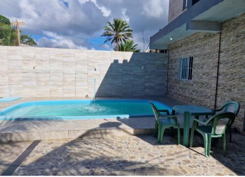 - une piscine avec 2 chaises, une table, une table et des chaises dans l'établissement Casa com piscina na ilha de itaparica, à Vera Cruz de Itaparica
