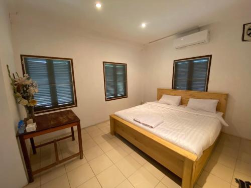 um quarto com uma cama, uma mesa e janelas em Mary’s Home Stay em Luang Prabang