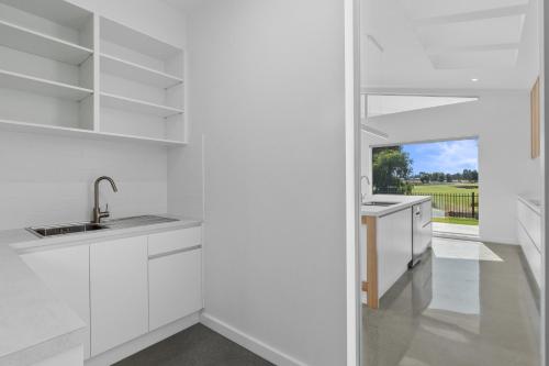 una cocina con armarios blancos y una ventana en Golf Fronted on the 6th Fairway, en Yarrawonga