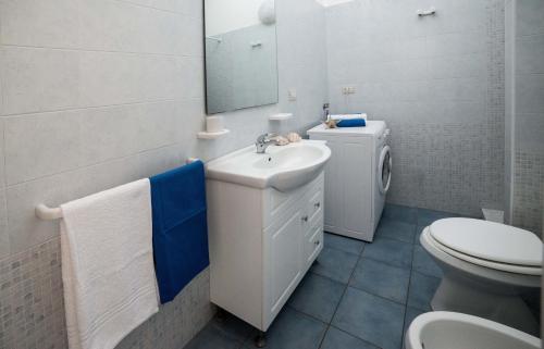 a bathroom with a sink and a toilet and a mirror at Le Bianche ville con patio privato a un passo dal mare in Torre Suda