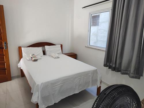 a bedroom with a white bed and a window at Casa Tropicana (2º andar) in Flecheiras