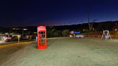 a red phone booth sitting in a field at night at โซพราว เขาค้อ So Proud Khaokho in Khao Kho