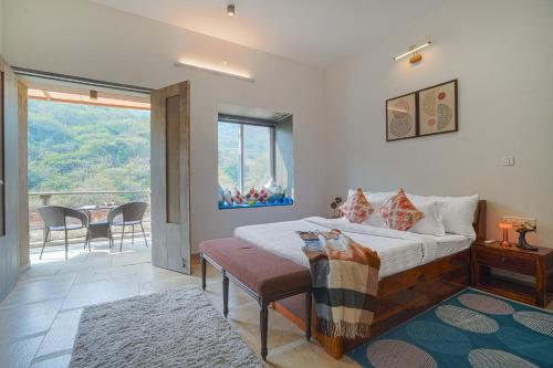 1 dormitorio con 1 cama y balcón con mesa en SaffronStays Moringa Valley Ashoka Villa, en Udaipur