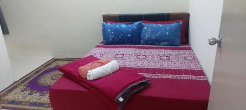 a bedroom with a bed with purple sheets and blue pillows at Bambob Homestay in Gambang
