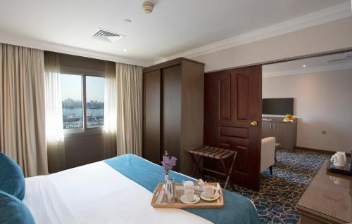杜拜的住宿－卡爾頓塔酒店，一间酒店客房,配有床和一张桌子,上面有杯子