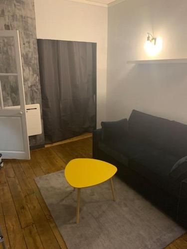 sala de estar con sofá negro y mesa amarilla en Appartement plein centre en Toulouse