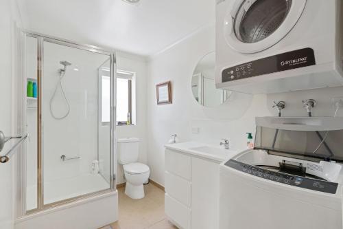 a white bathroom with a toilet sink and a microwave at 21 Shamrock Avenue Cowes in Cowes
