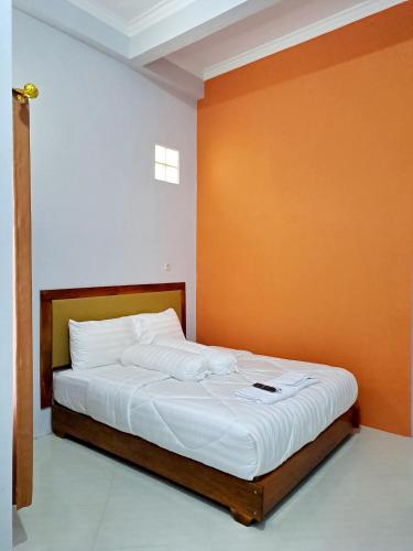a bed in a room with an orange wall at Kresna Guest House Syariah Pacitan in Pacitan