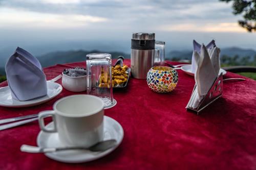 a table with a cup and plates of food on it at The Golden Sunrise Hotel in Nainital