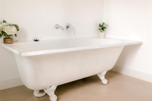 a white bath tub in a bathroom with flowers at The Terrace @ Scarborough NSW 