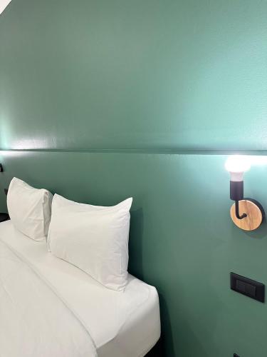 1 cama con almohadas blancas y una lámpara en la pared en NOW’S HOSTEL, en Ban Chang