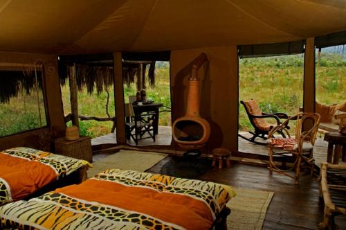 卡拉圖的住宿－Crater Forest Tented Lodge，一间设有两张床的客房和一个位于帐篷内的壁炉