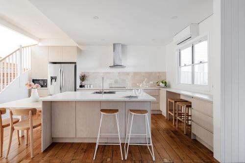a kitchen with white cabinets and a island with bar stools at The Terrace @ Scarborough NSW 