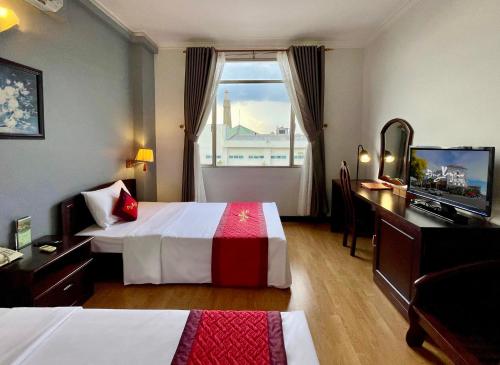 a hotel room with two beds and a desk and a window at Đông Xuyên Hotel in Long Xuyên