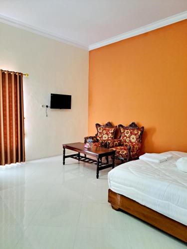 a bedroom with a bed and a couch and a table at Kresna Guest House Syariah Pacitan in Pacitan