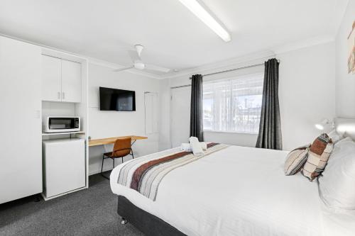 a bedroom with a bed and a desk and a microwave at Econo Lodge Chaparral Motel Ballina in Ballina