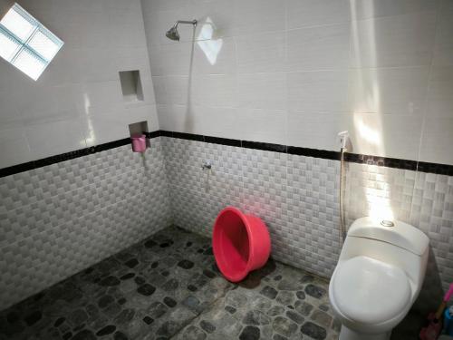 a bathroom with a white toilet and a red bowl at Puri Swantari Javanese Home Stay in Sleman