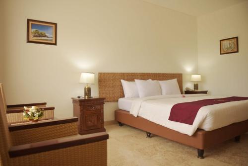 a bedroom with a large bed and a night stand at Puri Lovina in Lovina