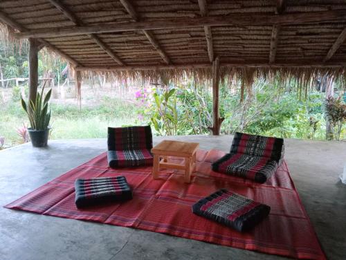 a patio with two chairs and a table on a red rug at The River Retreat Koh Mak in Ko Mak