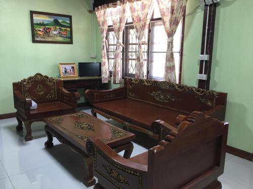 a living room with chairs and a table and windows at The Orange House Thailand - Baan P'Nae Homestay in Ban Khlong Bang Khrok