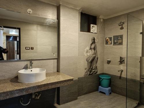 a bathroom with a sink and a statue of a woman at Hotel The King near mall rd mcleodganj in Dharmsāla
