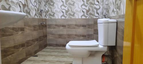La salle de bains est pourvue de toilettes blanches et d'un lavabo. dans l'établissement New White House Ratnapura, à Ratnapura