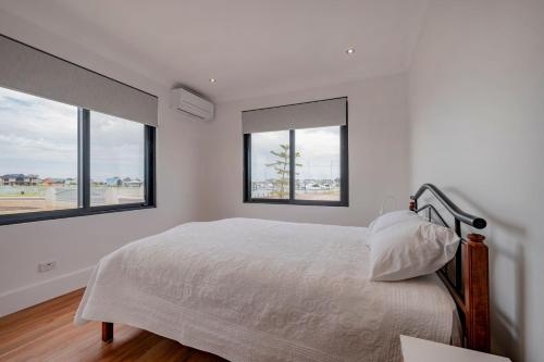a white bedroom with a bed and two windows at Port Lane Lower Apartment in Geographe