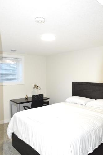 a bedroom with a large white bed and a desk at Secondary Suite, Separate Entrance NW Calgary in Calgary