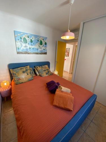 - une chambre avec un grand lit et une couverture orange dans l'établissement Rivage, au Barcarès