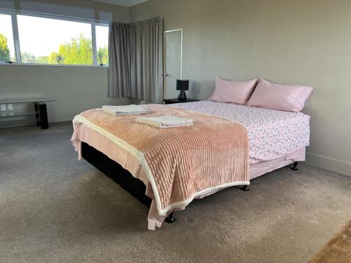 a bedroom with a large bed with pink pillows at Marvelous Munro in Hamilton
