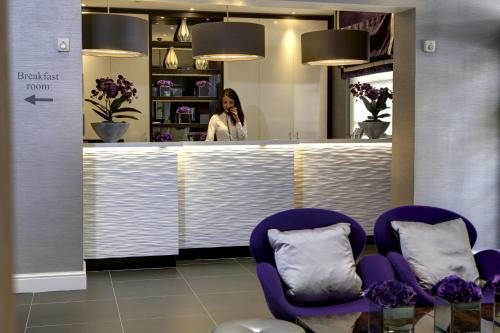 a woman standing behind a counter in a salon with purple chairs at Best Western Victoria Palace in London