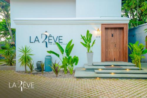 a white building with a wooden door and plants at LA RÊVE The Beach Villa in Malappuram