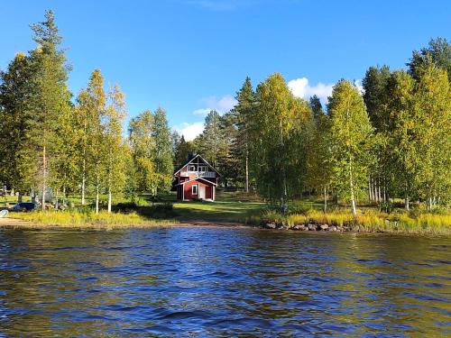 a red house on the shore of a lake at Villa Haaveranta - Private Villa by the lake in Rovaniemi